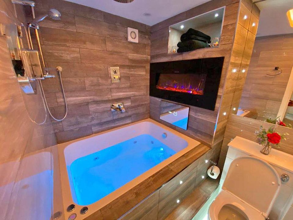 Recessed spotlights, mirror and feature LED lighting fitted in a tiled Birmingham bathroom